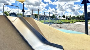 A playground with a slide, climbing structures, and a netted area.