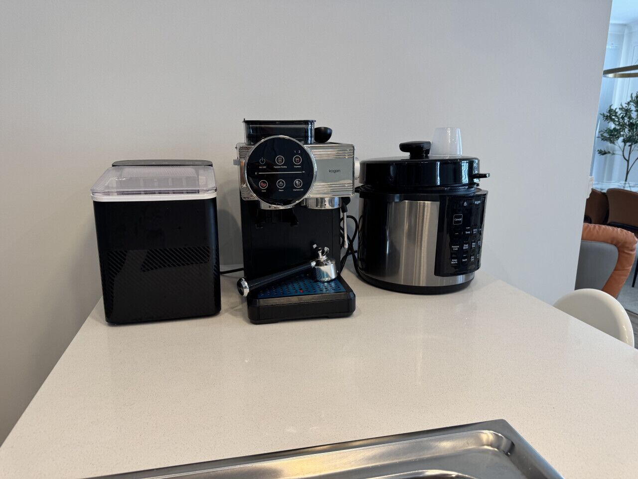 A kitchen with a coffee maker, a toaster, and a kettle on a white countertop.
