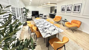 A modern dining area with a marble table, orange chairs, and a pendant light.