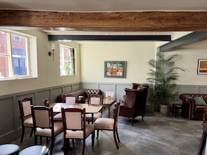 Un comedor con techo de madera, un ventanal grande, una mesa con sillas y una planta en maceta.