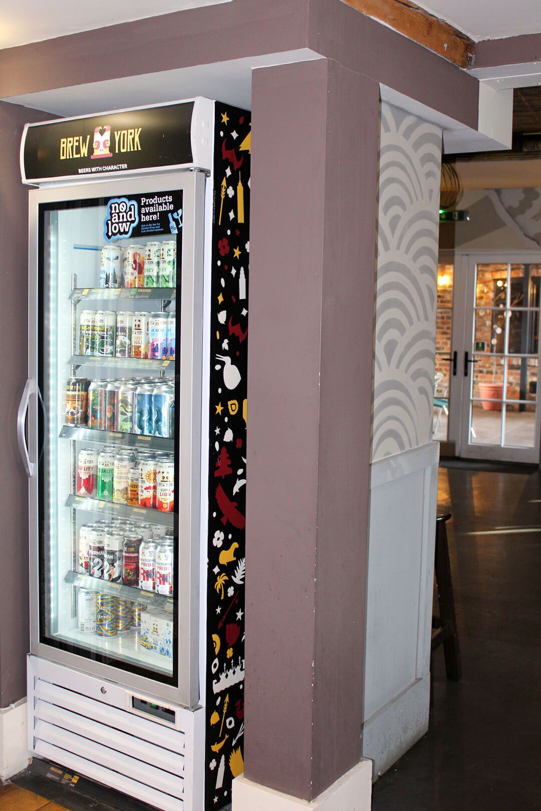 Mostrador refrigerado de bebidas con un cartel que dice 'BREW YORK' y 'CERVEZAS CON PERSONALIDAD'.