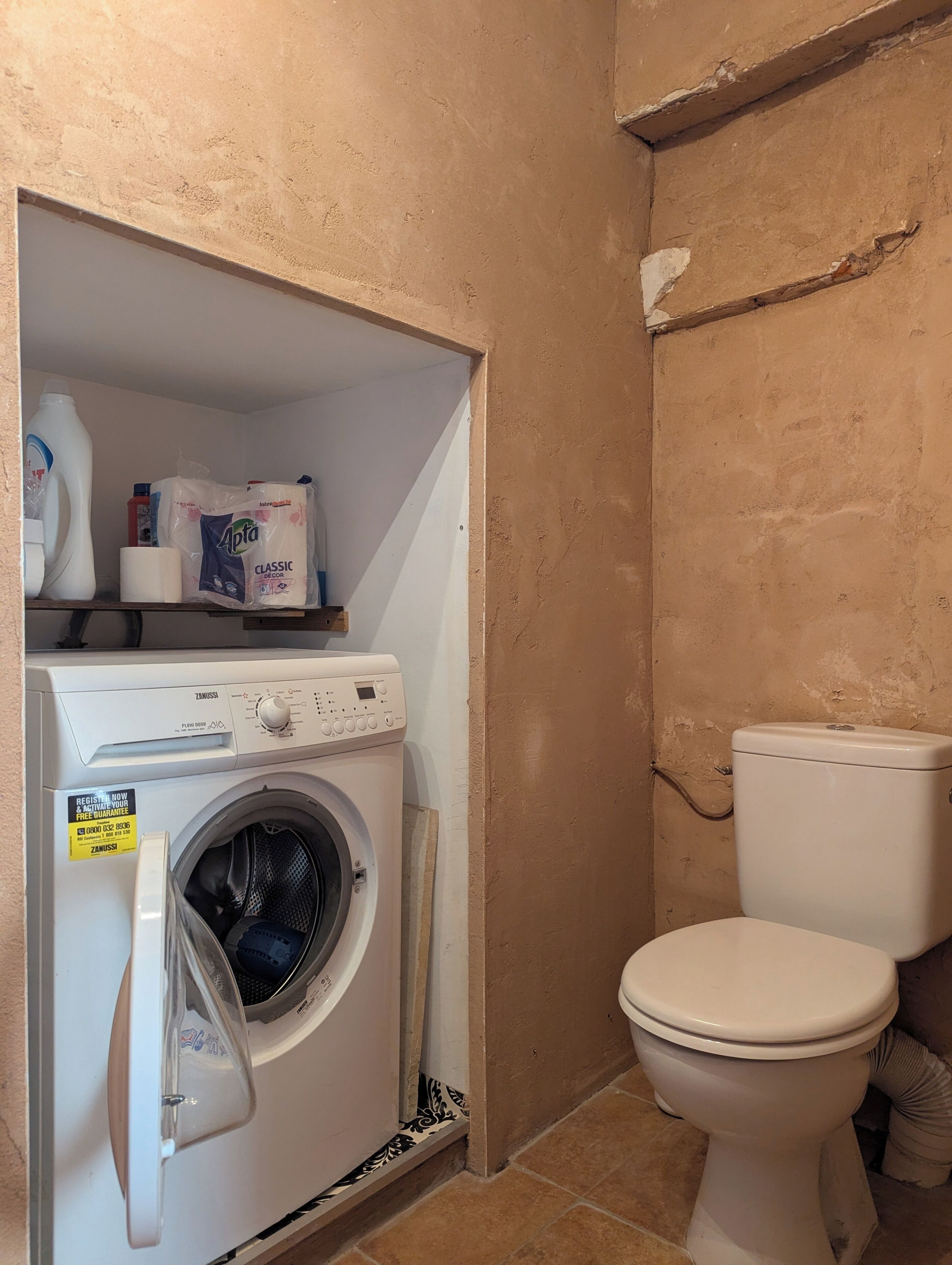 A laundry area with a washing machine, toilet, and cleaning supplies.
