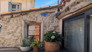 Un muro de piedra con una ventana, plantas en macetas y una puerta.