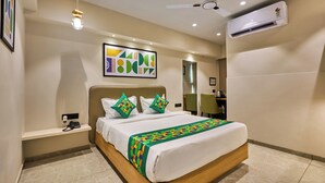 Une chambre d’hôtel équipée d’un lit, d’un téléphone sur la table de chevet, d’un ventilateur de plafond, d’un climatiseur et d’une œuvre d’art accrochée au mur.