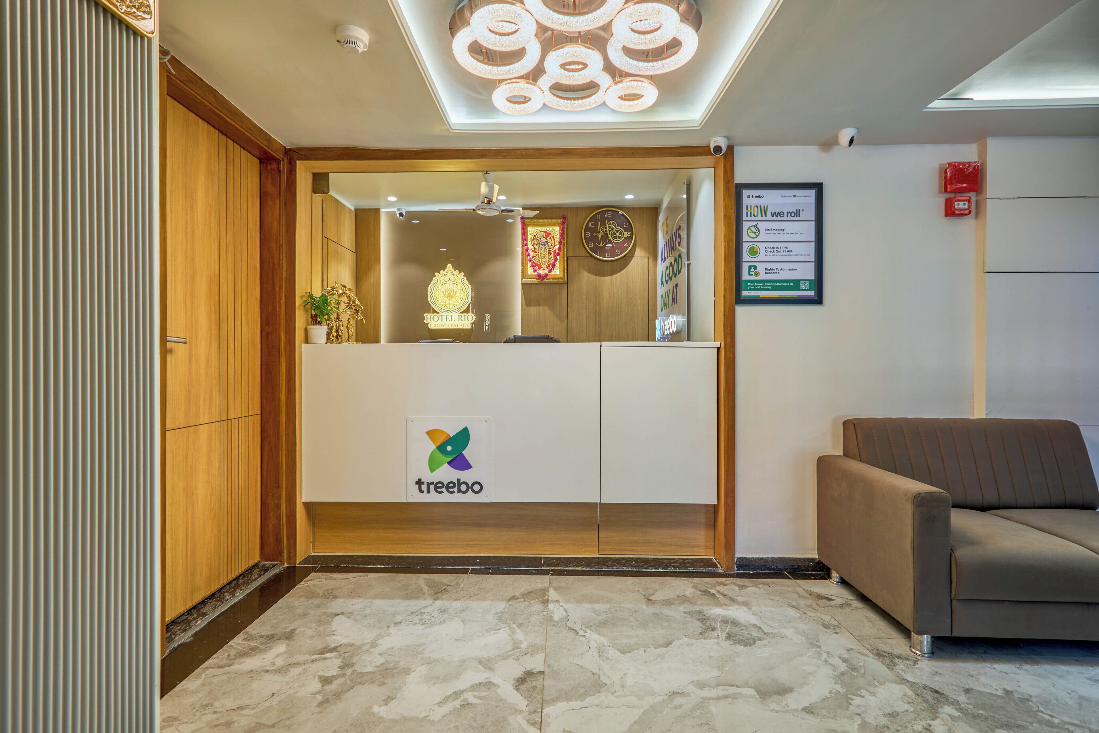 A hotel reception area with a wooden reception desk, a logo, and a signboard.