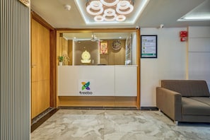 A hotel reception area with a wooden reception desk, a logo, and a signboard. - Treebo Rio Crown Palace (Ahmedabad)