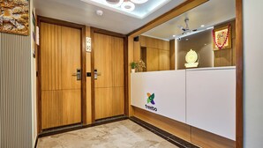 Un hall d'hôtel avec des portes en bois, un comptoir d'accueil et un ventilateur de plafond.