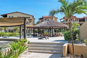 A resort with a thatched gazebo, outdoor seating, and a pool area. - Spacious Condo w/ Balcony, Pools + Ocean Views (San Pedro Town)