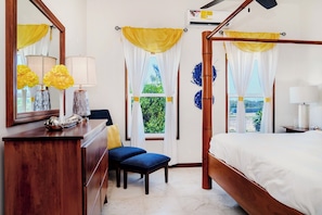 A bedroom with a wooden bed, a desk with a lamp, a chair, and a window with curtains. - Spacious Condo w/ Balcony, Pools + Ocean Views (San Pedro Town)