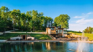 Ein modernes Haus mit Teich, Brunnen und einem gepflegten Rasen.