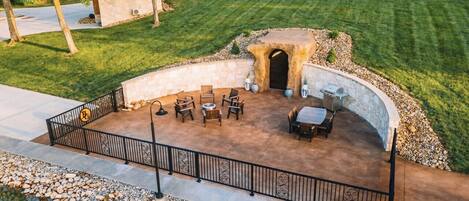 Un patio con asientos de piedra, un hogar y una pequeña construcción de piedra.