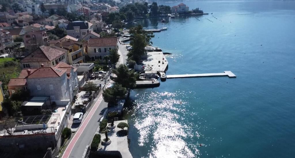 An aerial view of a coastal town with buildings, a road, and a dock.