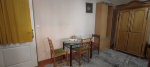 Una habitación con una mesa de comedor, dos sillas, un armario y una puerta adornada con cortinas amarillas.