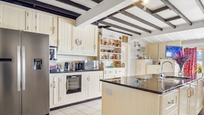 Una cocina moderna con un refrigerador de acero inoxidable, dispensador de agua, hervidor y cafetera.