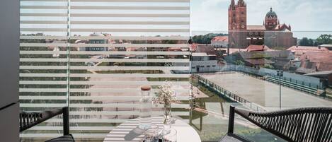 Habitación de hotel con vistas a un paisaje urbano, incluyendo una iglesia destacada con dos torres.