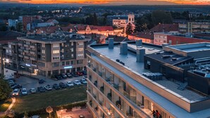 Un hotel de varios pisos con zonas de estar al aire libre y vistas de la ciudad circundante.