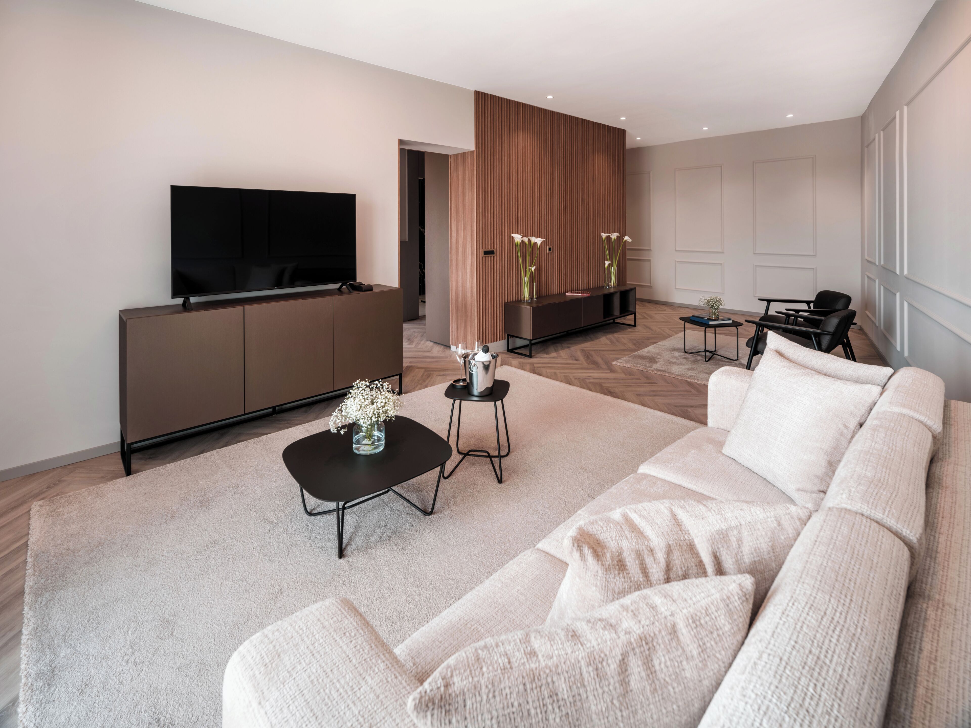 A modern living room with a sofa, coffee table, TV, and a wooden accent wall.