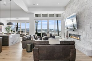 Ein modernes Wohnzimmer mit Kamin, Ledersofa und großem Fernseher an der Wand.