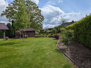 Un jardin bien entretenu, agrémenté d’un belvédère, d’un petit abri de jardin et de haies soigneusement taillées.