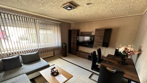 Uma sala de estar moderna com sofá, mesa de centro, TV e área de jantar.