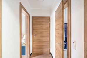 A hallway with a wooden door, a light switch, and a power outlet on the wall. - Apartment "Landleben 2" with Shared Terrace, Private Garden, and Wi-Fi (Erkelenz)