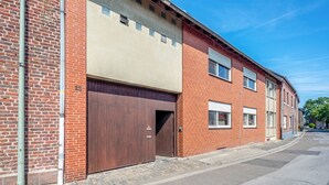 Een gebouw van baksteen met twee verdiepingen, een grote garage deur, een vluchttrap en een helderblauwe lucht.