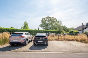 Two parked cars on a paved driveway with a hedge and a tree in the background. - Apartment "Landleben 2" with Shared Terrace, Private Garden, and Wi-Fi (Erkelenz)