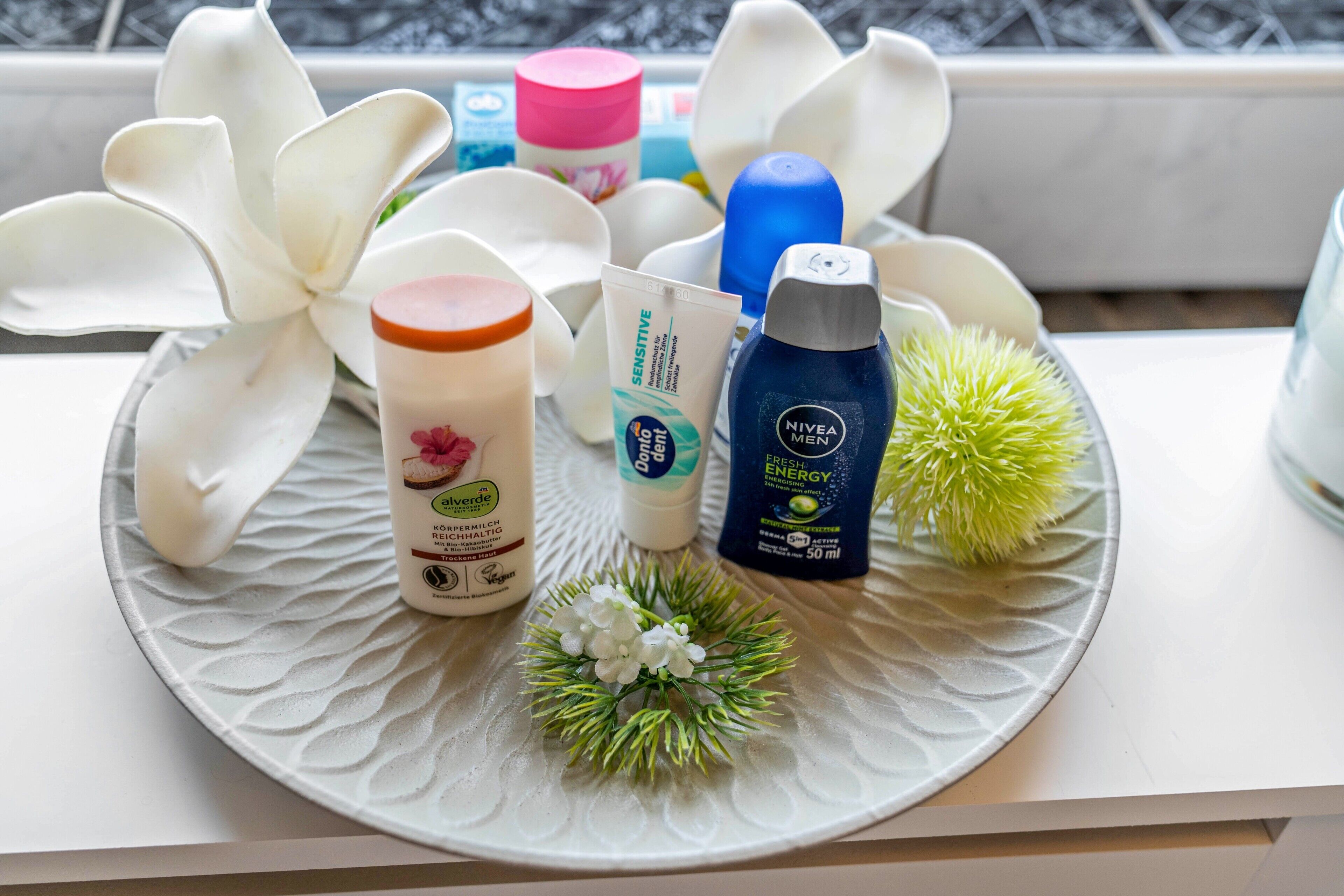 A tray with various personal care products, including a bottle of Nivea Men Fresh Energy, a jar of aloe vera gel, and a container of body lotion.