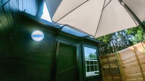 A wooden structure with a window, a door, and a large umbrella providing shade.