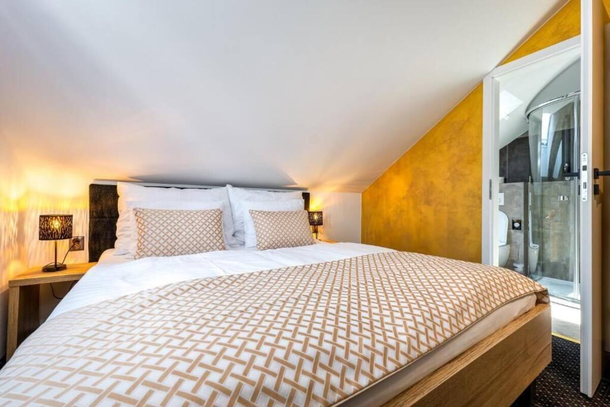 Un dormitorio con cama, lámparas de noche, puerta de ducha de vidrio y vista al exterior.