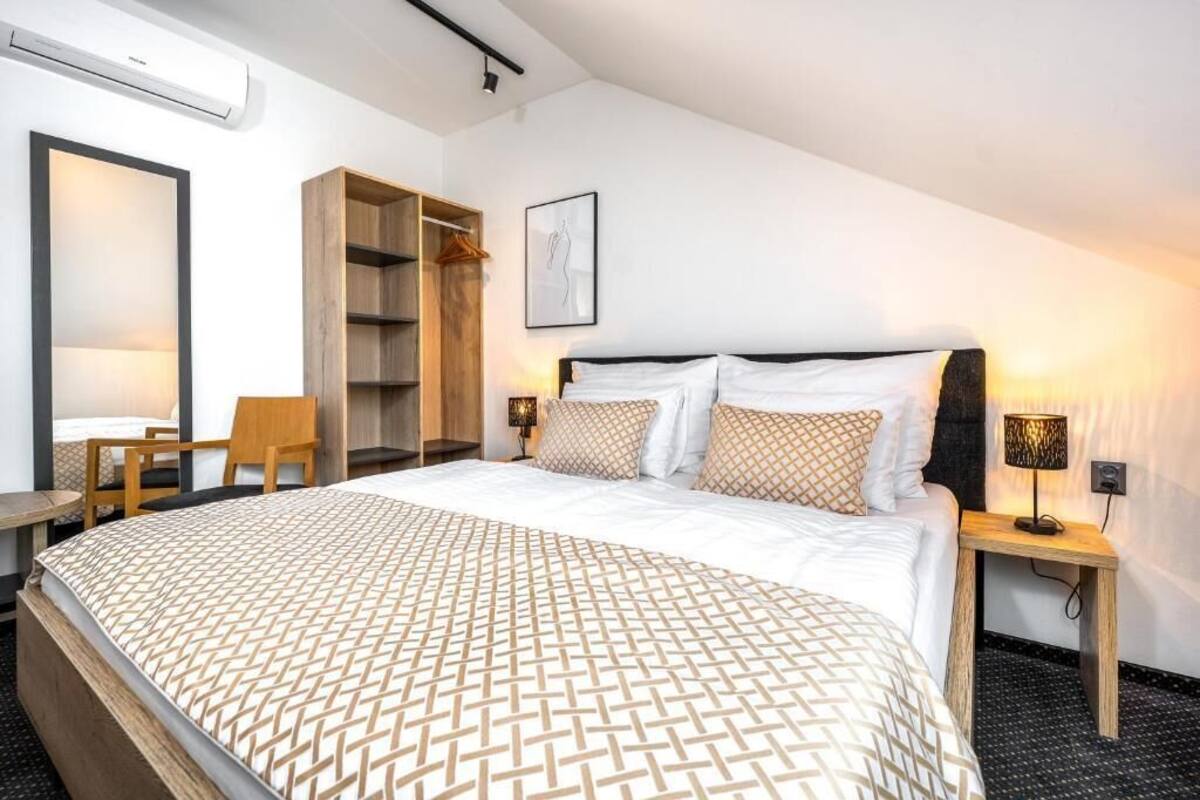 Una habitación de hotel con una cama grande, un armario de madera, un escritorio y una silla.
