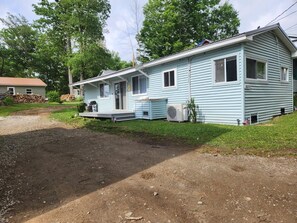 A single-story house with a porch, an air conditioning unit, and a small front yard.