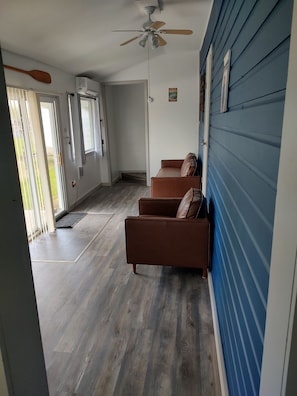 A room with a brown leather sofa, a ceiling fan, and a blue wall.