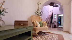 A room with a wicker chair, a green desk, a patterned rug, and a staircase in the background. - Hotel La Casa de Mis Marias (Tlaquepaque)