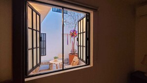 A room with a sliding door leading to an outdoor seating area with a table, chairs, and a potted plant. - Hotel La Casa de Mis Marias (Tlaquepaque)