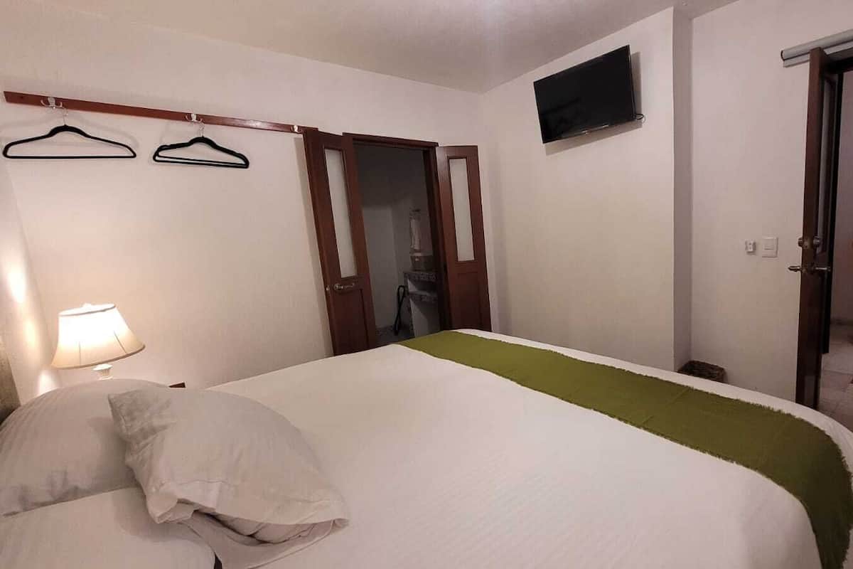 Habitació d'hotel amb un llit, televisió, una cadira i una porta.