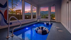 Ein Hallenbad mit freiem Blick auf Berge und einen Sonnenuntergang.