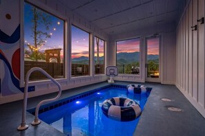 Ein Hallenbad mit freiem Blick auf Berge und einen Sonnenuntergang.