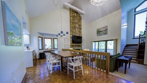 Amplia sala de estar con suelo de madera, una mesa de comedor y una chimenea de piedra.