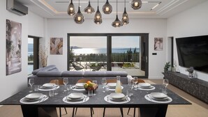 Een moderne eetruimte met een grote tafel voor zes personen, een bank en een balkon met uitzicht.
