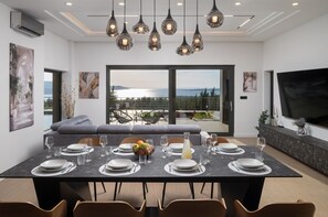 Ein moderner Essbereich mit großem Tisch für sechs Personen, einer Couch und einem Balkon mit Blick.