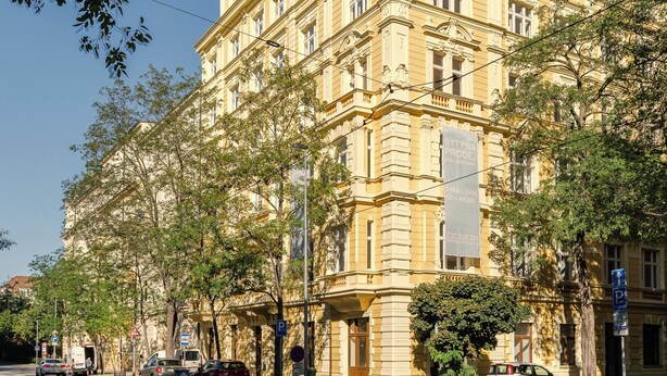 A multi-story building with classical architecture, a street in front, and parked cars. - Top floor studio with balcony and smart design (Hlavní město Praha)