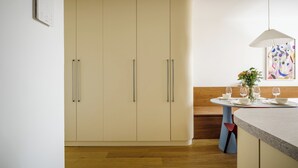 A modern kitchen with wooden cabinets, a dining table set with glasses and a vase of flowers, and a pendant light. - Top floor studio with balcony and smart design (Hlavní město Praha)