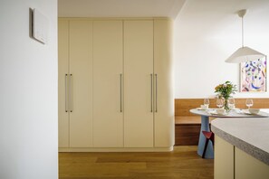 Eine moderne Küche mit Holzausstattung, einem Esstisch gedeckt mit Gläsern und einer Blumenvase, sowie einer Pendelleuchte.