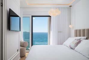 Ein Schlafzimmer mit Bett, Fernseher, Sessel und Meerblick.