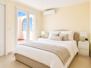 Ein Schlafzimmer mit einem Bett, zwei Nachttischen, einem Fenster mit Blick und einer Klimaanlage.