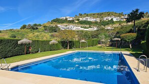 Piscina com vista desobstruída da paisagem ao redor, incluindo uma encosta com edifícios.