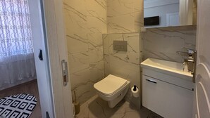 A bathroom with a toilet, sink, and mirror. - MÜREFTE SUİTE (Sarkoy)