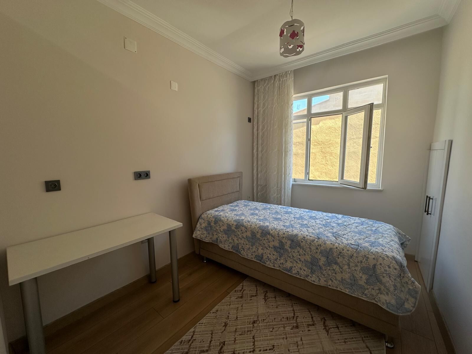 Une chambre à coucher avec un lit, un bureau, une fenêtre et un radiateur.