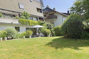 En boligbygning med skråt tag, balkon og velplejet græsplæne.
